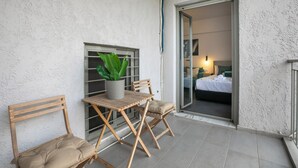 A small outdoor seating area with a table and two chairs, a potted plant, and a sliding glass door leading to a bedroom. - Cassiopeia - Studio & Balcony in Athens (Athens)