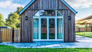 Une cabane en bois avec un toit à pignon, de grandes portes-fenêtres coulissantes et un petit espace porche.