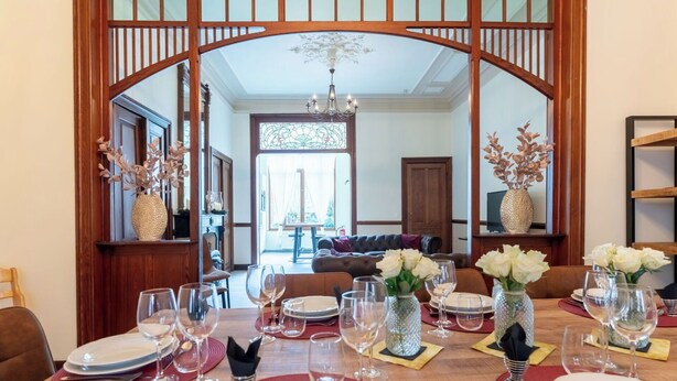 A dining area with a wooden table set for a meal, surrounded by chairs. - Beautiful private villa for 10 guests with WIFI and TV (Blankenberge)