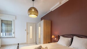 Ett sovrum med en säng, ett sängbord, en lampa och en hängande taklampa.
