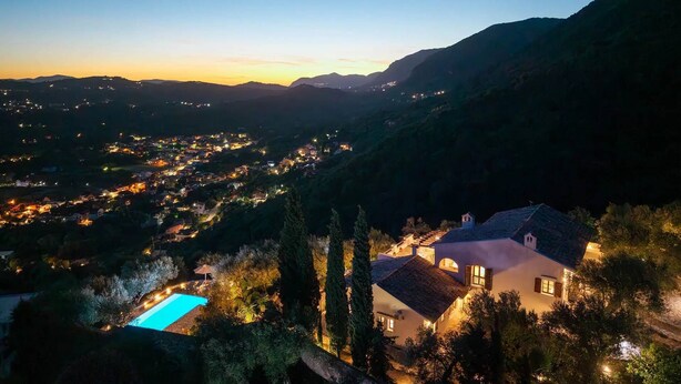 A hillside villa with a swimming pool, surrounded by trees and overlooking a valley with distant lights. - Spartilas Villas (Corfu)