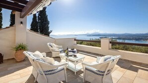 A terrace with wicker furniture, a table, and a potted plant. - Spartilas Villas (Corfu)