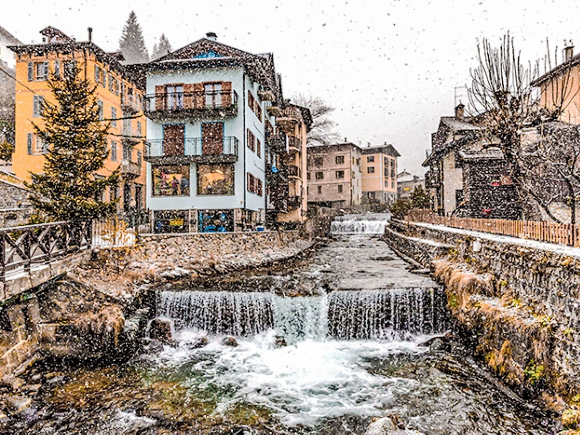 Eine verschneite Stadt mit einem Fluss, der sich hindurchschlängelt, umgeben von Häusern.