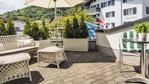 An outdoor patio area with wicker furniture, a large umbrella, and potted plants. - Lovely apartment for 4 guests with WIFI, TV, balcony, pets allowed and panoramic view (Laax)