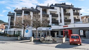 A multi-story hotel with a modern architectural design, featuring balconies and a prominent entrance. - Lovely apartment for 4 guests with WIFI, TV, balcony, pets allowed and panoramic view (Laax)