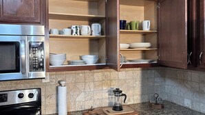 Een keuken met houten kastjes, een roestvrijstalen magnetron, een koffiezetapparaat en een granieten aanrecht.