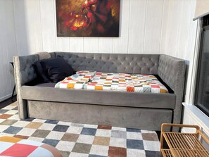 A grey tufted sofa with a checkered blanket and a dark pillow. A colorful abstract painting hangs above. - Simple Comforts,Midway Hollow Dallas:WFH Office: Relocations.Pets welcome (Dallas)