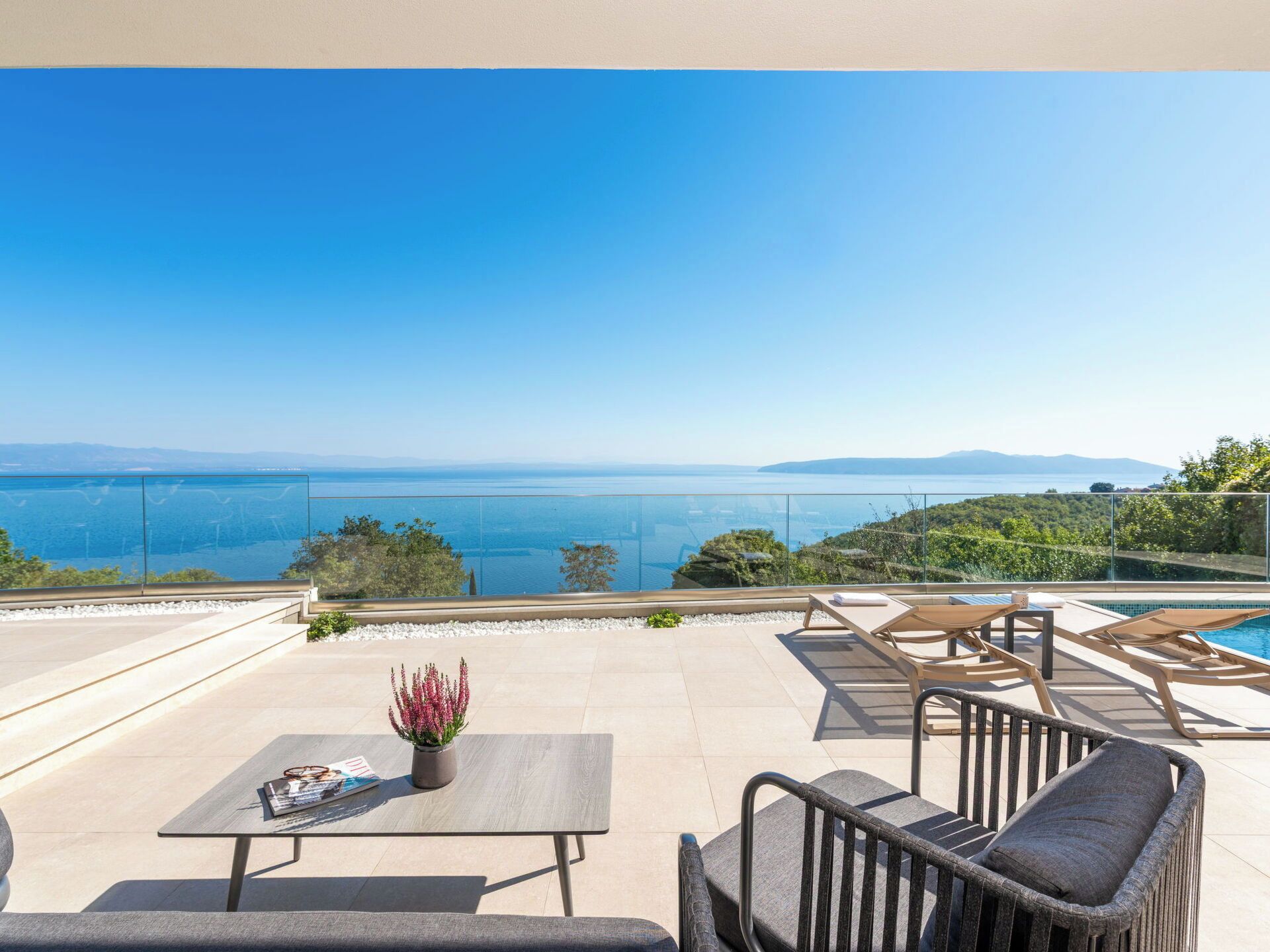 A terrace with a pool, outdoor furniture, and a view of the sea.