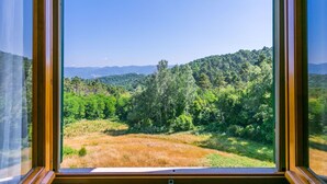 Una ventana con vistas a un paisaje boscoso y montañas distantes.
