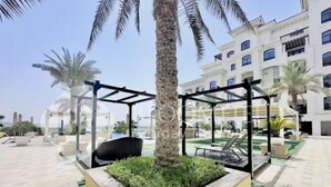 A courtyard with a palm tree, outdoor seating, and a building in the background.