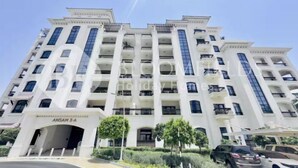 A multi-story hotel with a central entrance, balconies on each floor, and a clear sky.