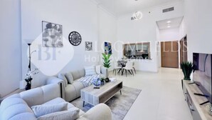 A modern living room with a sofa, coffee table, and a dining area with chairs and a table.