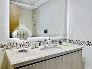 A bathroom with a large mirror, a sink, and a shower. - G06-Bloomfields Spacious 1Br Ansam (Abu Dhabi)