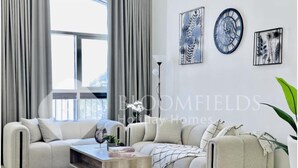 A modern living room with a sectional sofa, a coffee table, and artwork on the walls.