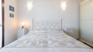 Un dormitori amb llit, tauells de nit, aplics de paret i un armari.