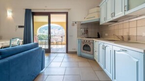 Cuina compacta amb armaris blaus clars, forn integrat i una petita zona de menjador amb un sofà blau.