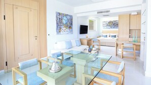 Una sala de estar moderna con una mesa de comedor de vidrio, un sofá y una zona de cocina con televisor.