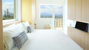 Un dormitorio con cama, televisor, mesita de noche y vistas al exterior.