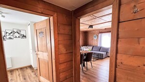 Et interiør i træ med et spiseområde, en sofa og et ur på væggen.