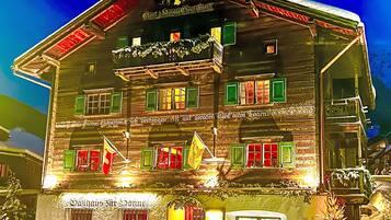 Ein traditionelles Holzgebäude mit mehreren Fenstern, von denen einige mit grünen Fensterläden versehen sind, und einem Schild, das es als Restaurant kennzeichnet.