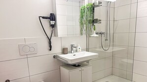 Et moderne badeværelse med toilet, håndvask og brusebad.