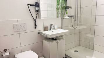 Ein modernes Badezimmer mit Toilette, Waschbecken und Dusche.
