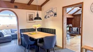 A dining area with a wooden table, grey upholstered chairs, and a vase of flowers. - Beautiful apartment for 7 people with WIFI, TV, balcony, pets allowed and panoramic view (Klosters Platz)