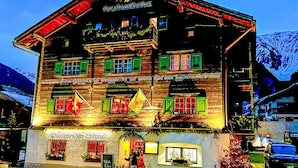 A traditional wooden building with multiple windows and a sign indicating it is a restaurant. - Beautiful apartment for 7 people with WIFI, TV, balcony, pets allowed and panoramic view (Klosters Platz)