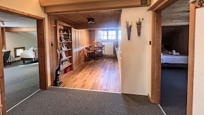 A hotel corridor with wooden flooring, a dining area with a table and chairs, and a room with a bed and a window. - Beautiful apartment for 7 people with WIFI, TV, balcony, pets allowed and panoramic view (Klosters Platz)