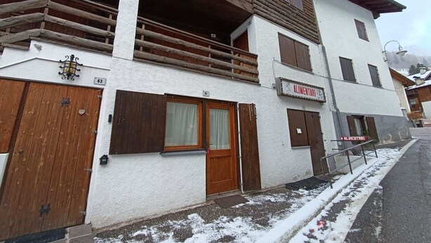 Un edificio de dos pisos con balcones de madera y un letrero que dice 'Alimentari'.