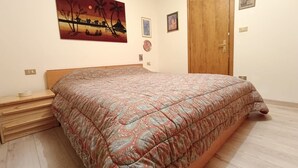 Un dormitorio con una cama grande, un cabecero de madera, una mesita de noche y un cuadro en la pared.