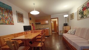 Una sala de estar acogedora con una mesa de comedor de madera y sillas, un sofá y un televisor.