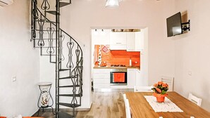 Een moderne keuken met witte kasten, een oranje achterwand en een houten eettafel met witte stoelen.