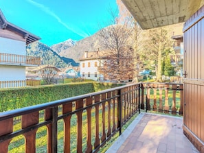 Ein Balkon mit Holzgeländer, der einen ordentlich gestutzten Heckenstreifen und einen Blick auf die Berge bietet.