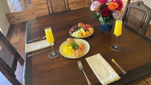 Taula de dinar posta amb plats de menjar, verres de suc de taronja i un ram de flors.