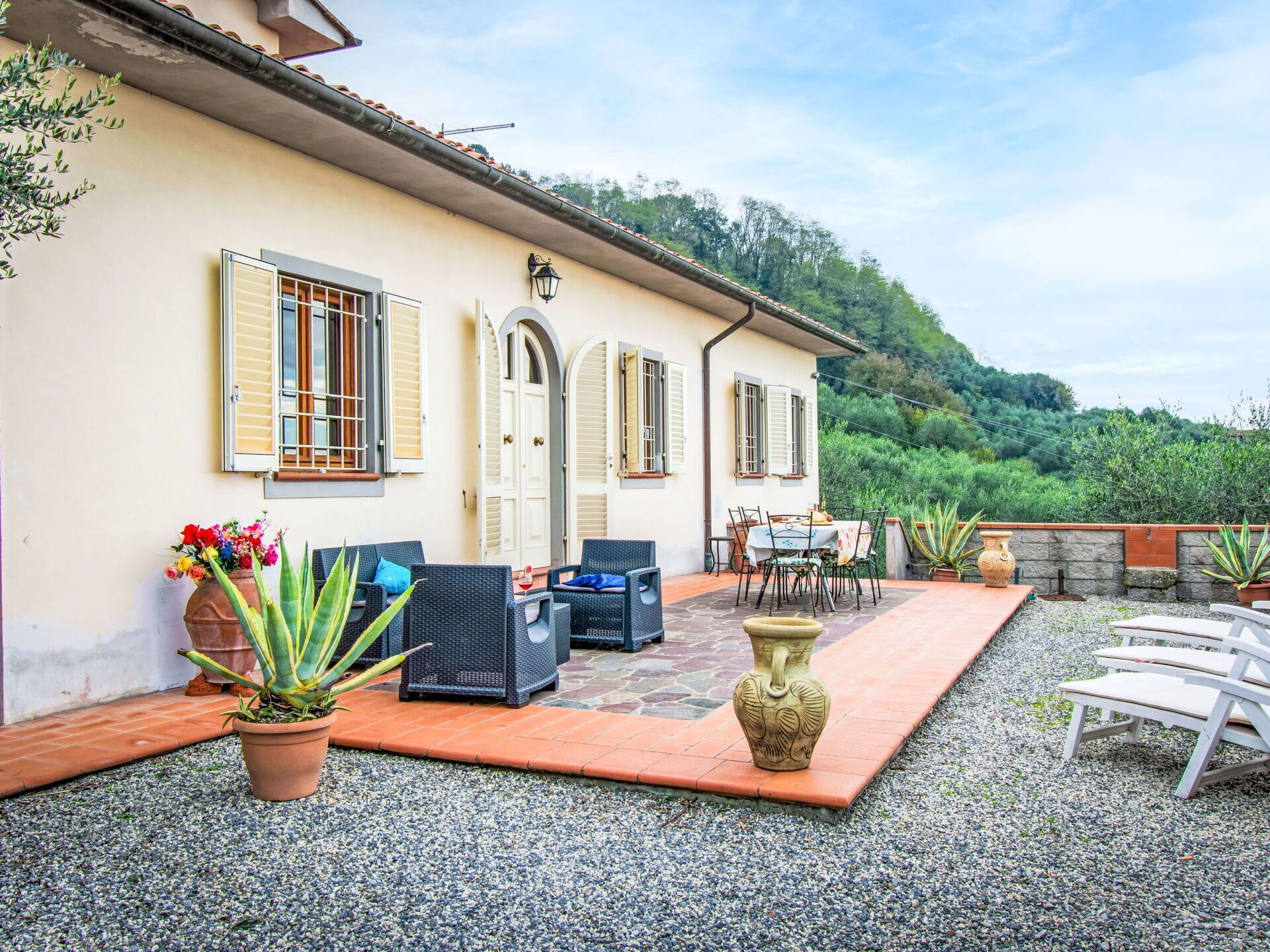 A villa with a patio, outdoor seating, and a view of the hills.