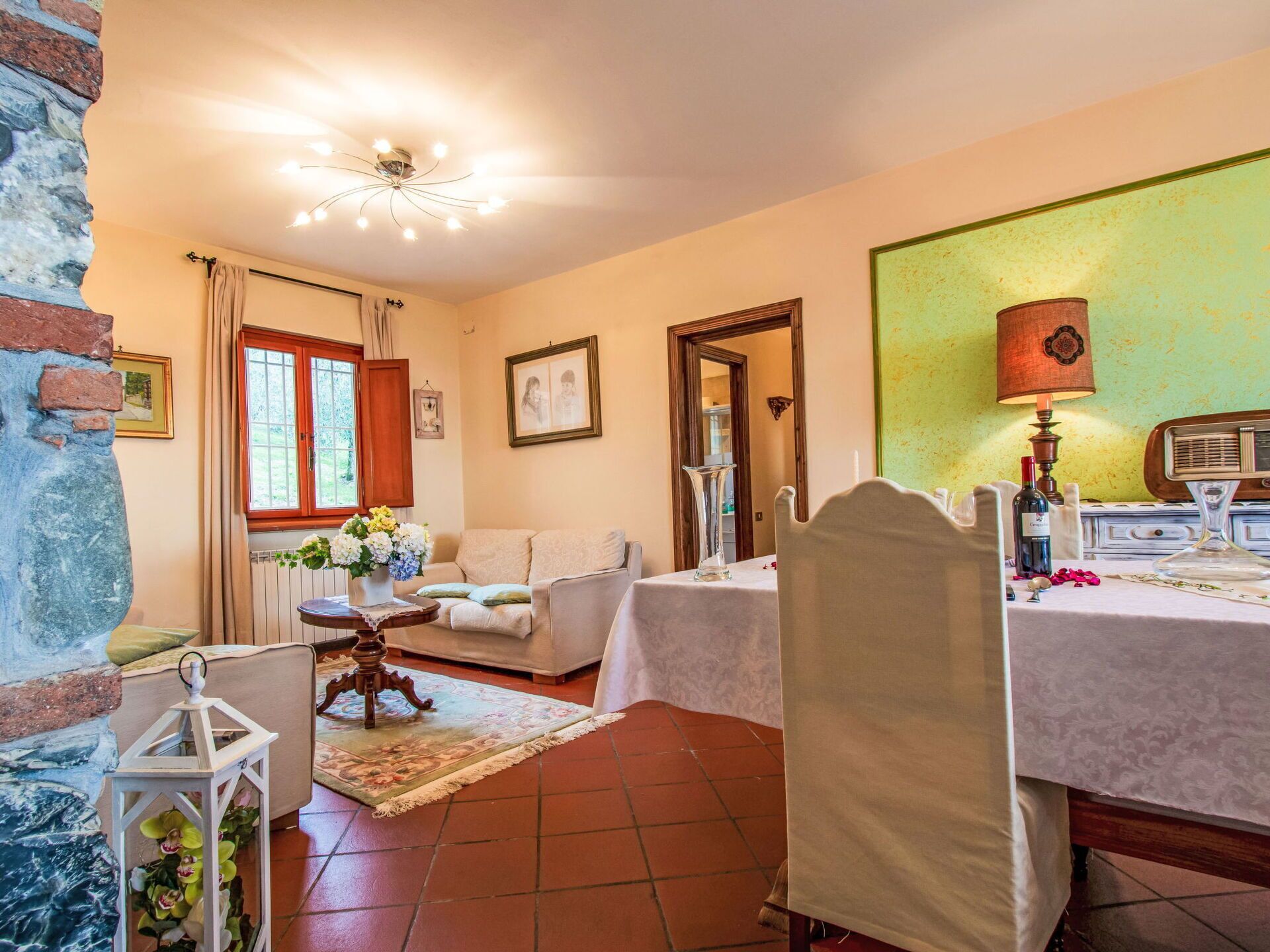 A cozy room with a sofa, a dining table set for two, and a vintage radio.
