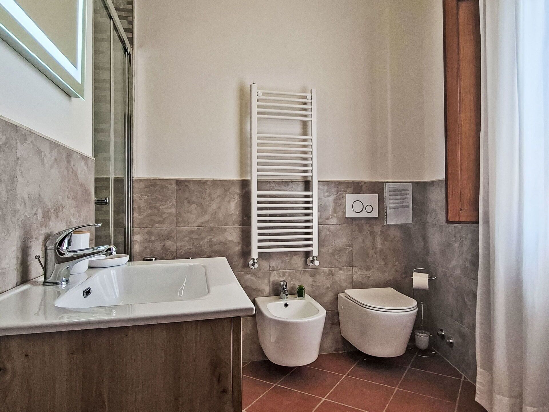 Ein Badezimmer mit Waschbecken, Bidet, Toilette, Handtuchhalter und Spiegel.