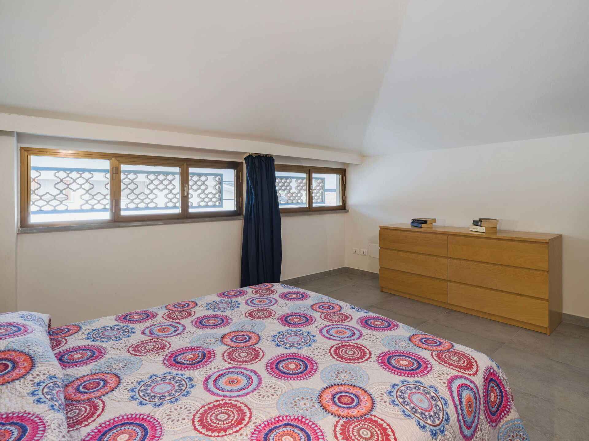 Un dormitorio con cama, cómoda y ventana con cortina.