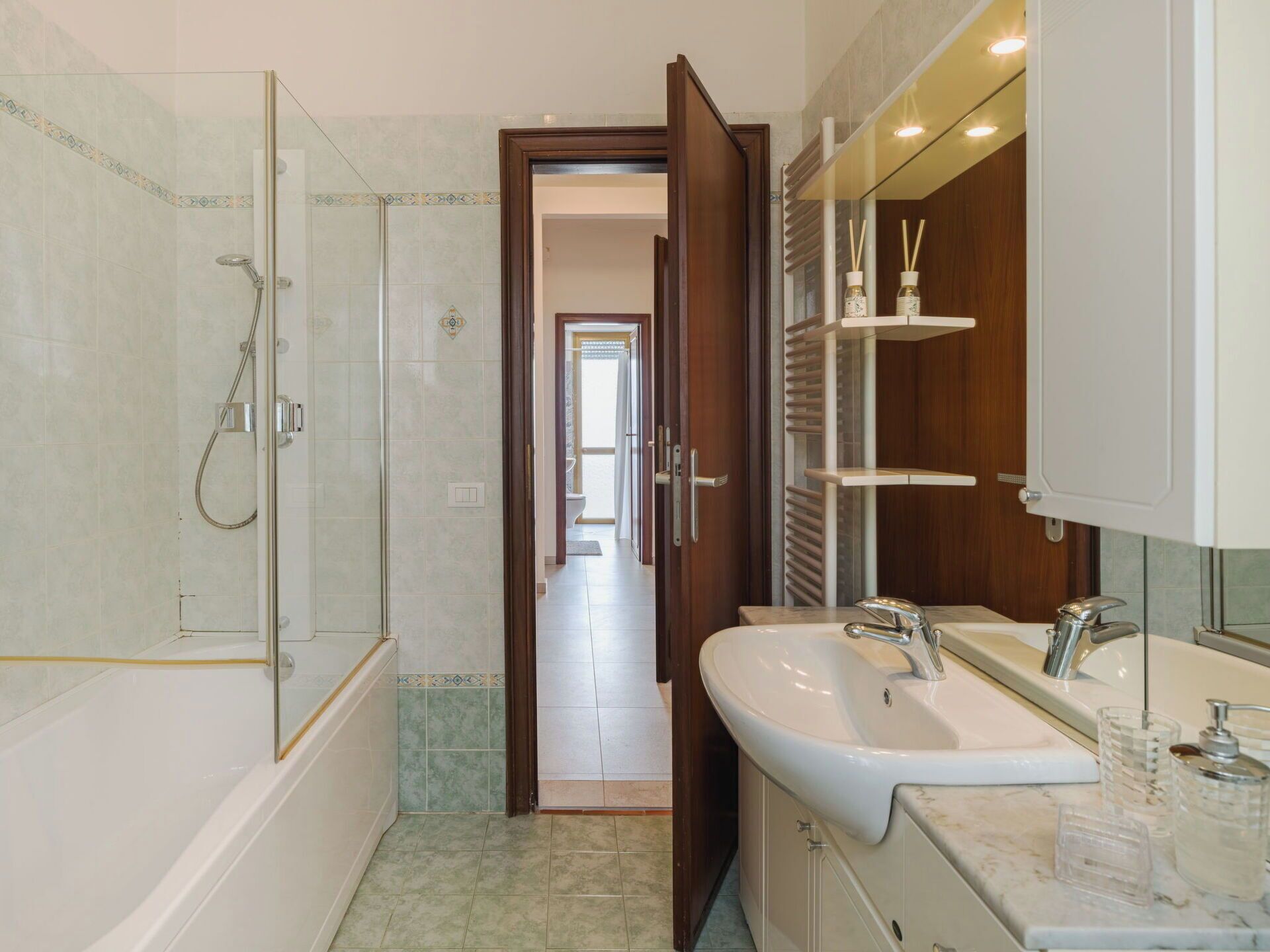 A modern bathroom with a glass-enclosed shower, a white sink with a marble countertop, and wooden cabinets.