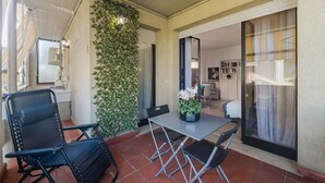 Un patio techado con una mesa y sillas, una planta en la pared y vista hacia el interior.