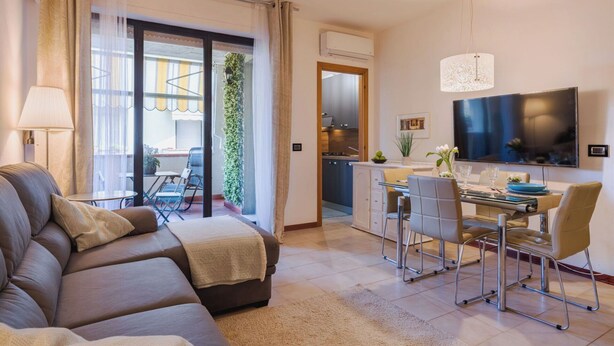 Una sala moderna con sofá, mesa de comedor, sillas y televisor.