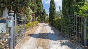 Un camino de grava que conduce a una entrada con puerta y pared de piedra.