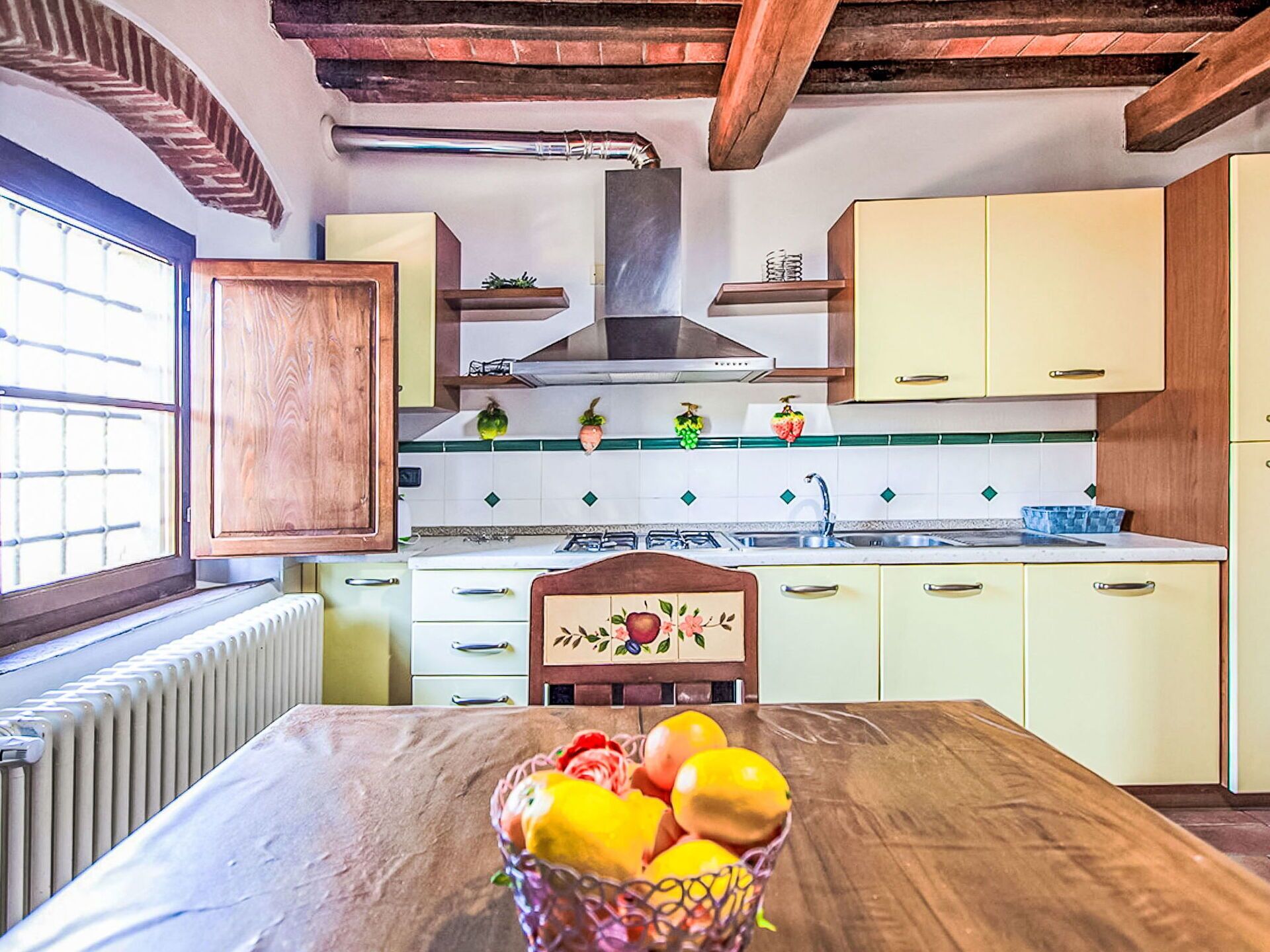 Una cucina con mobili in legno, un'isola centrale e una ciotola di frutta.