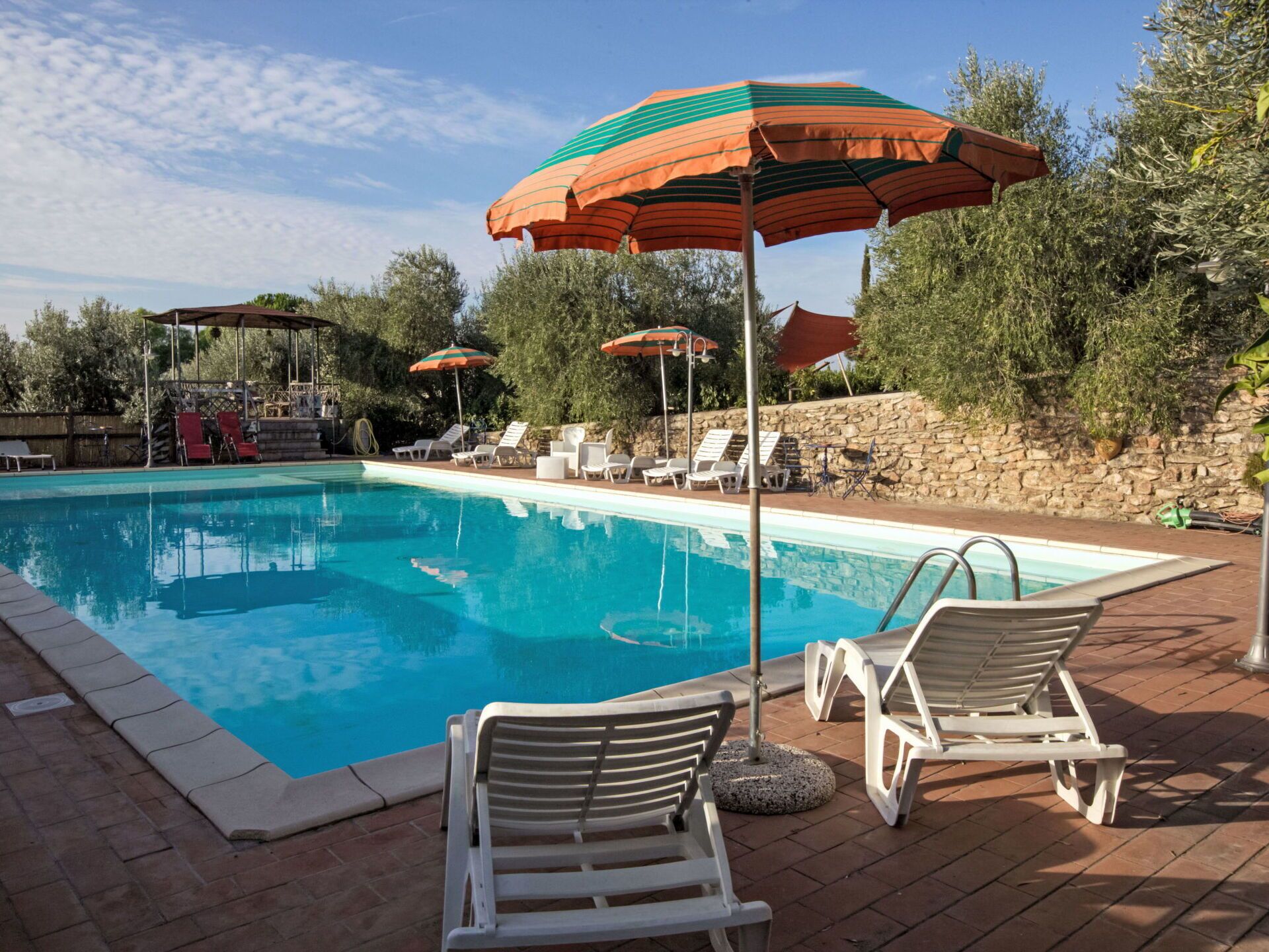 Una piscina con lettini e ombrelloni.
