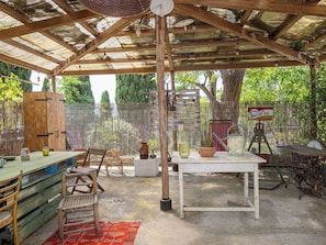 Un patio al aire libre con mesa y sillas de madera, un colgante de luz y un cartel de Esso Extra Aceite de Motor.