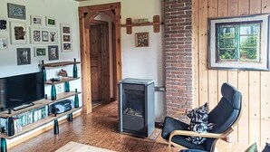 Ein gemütliches Wohnzimmer mit Kamin, Holzbalken und einem Fernseher.