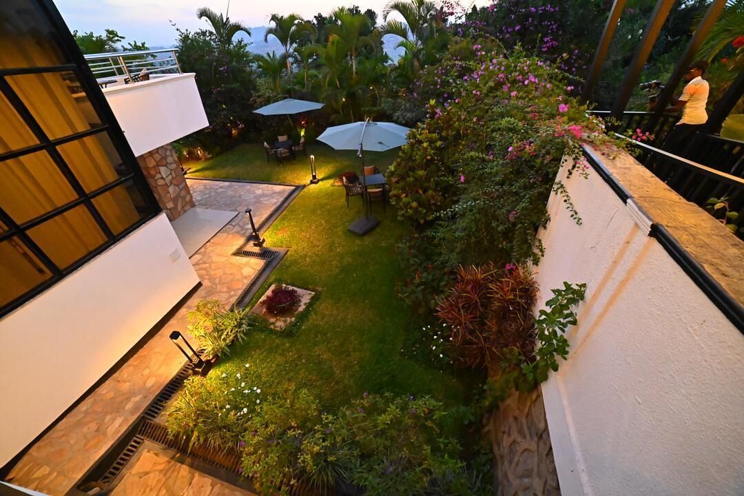 Un jardín en la azotea con mobiliario exterior, un sendero de piedra y abundante vegetación.