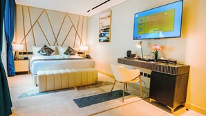 A modern hotel room with a bed, bedside tables, a desk, and a TV displaying a welcome message. - Hotel Noesis  (Kampala)