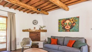 A living room with a sofa, chairs, a wooden coffee table, a fireplace, a clock, and a painting. - Cosy apartment for 4 people with WIFI, TV, patio, pets allowed and panoramic view (Gavorrano)